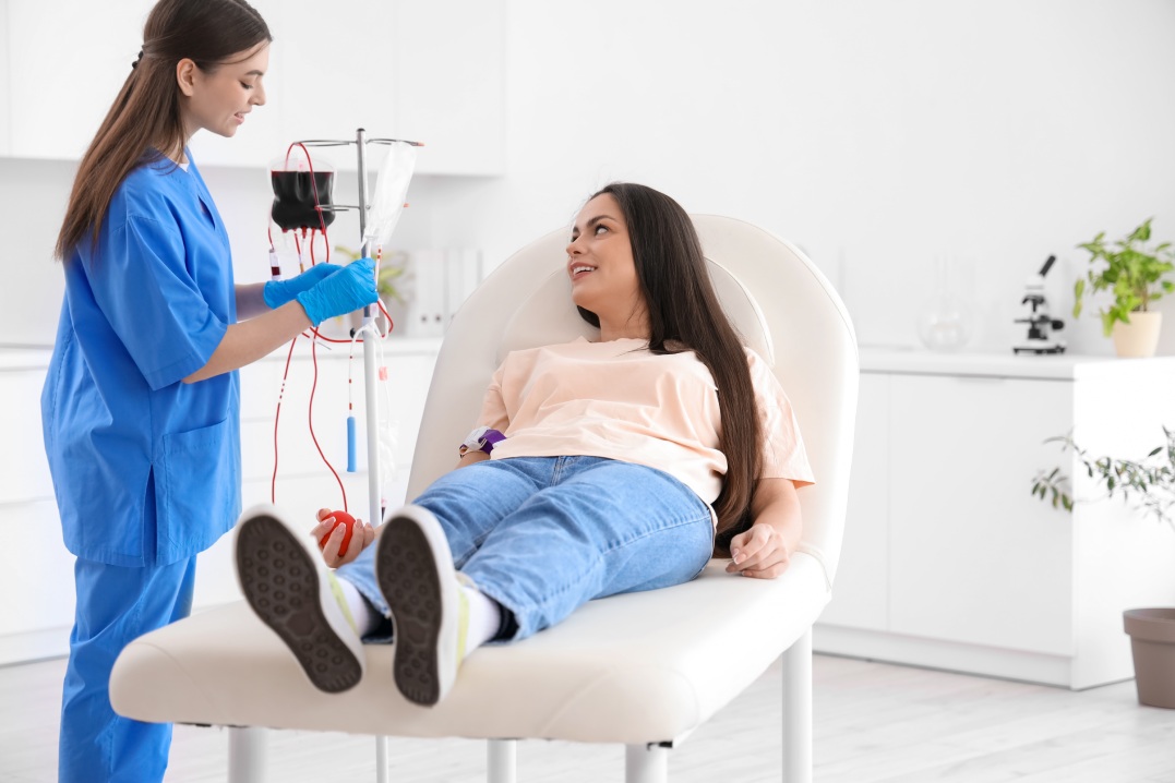 Female nurse preparing young donor for blood transfusion in clinic